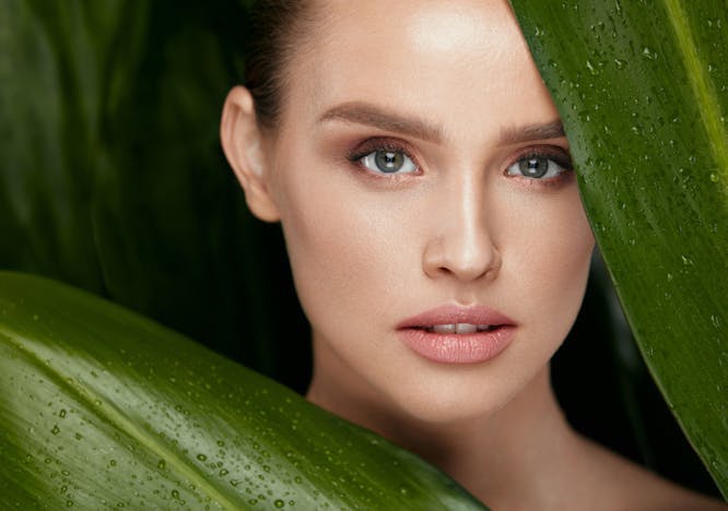 Gesicht einer Frau zwischen grünen Blätter