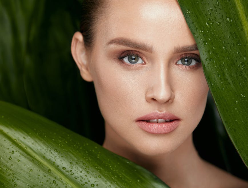 Gesicht einer Frau zwischen grünen Blätter