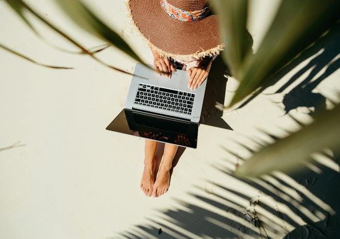 Frau mit Laptop unter Palmen am Strand