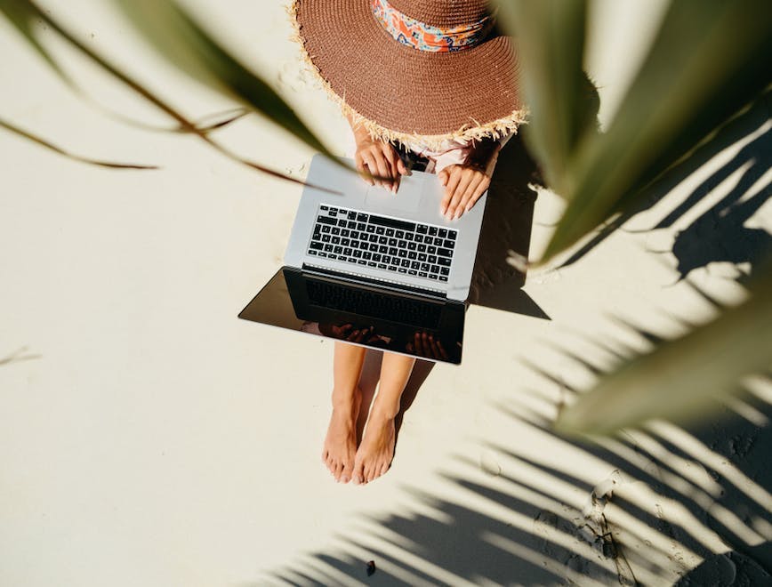 Woman sitting under palms with laptop