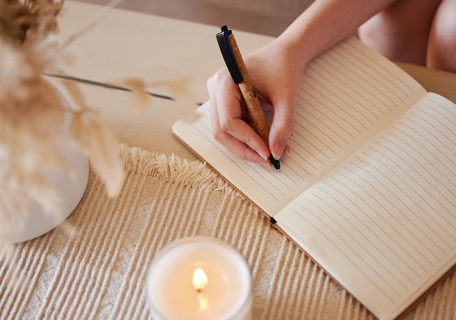 person writing pen candle